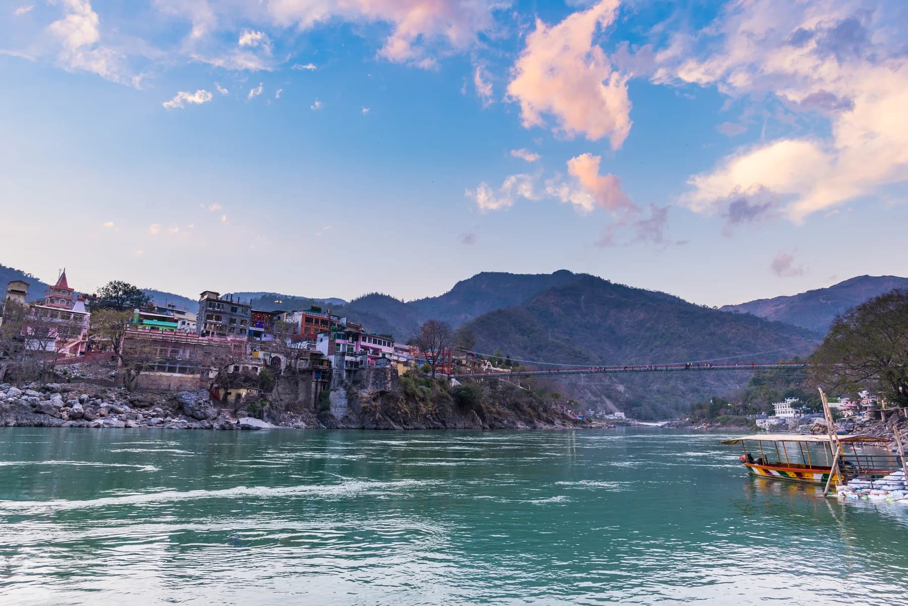 Cityscape of Rishikesh at sunset, holy town and travel destination in India. Colorful sky and clouds reflecting over the Ganges River.